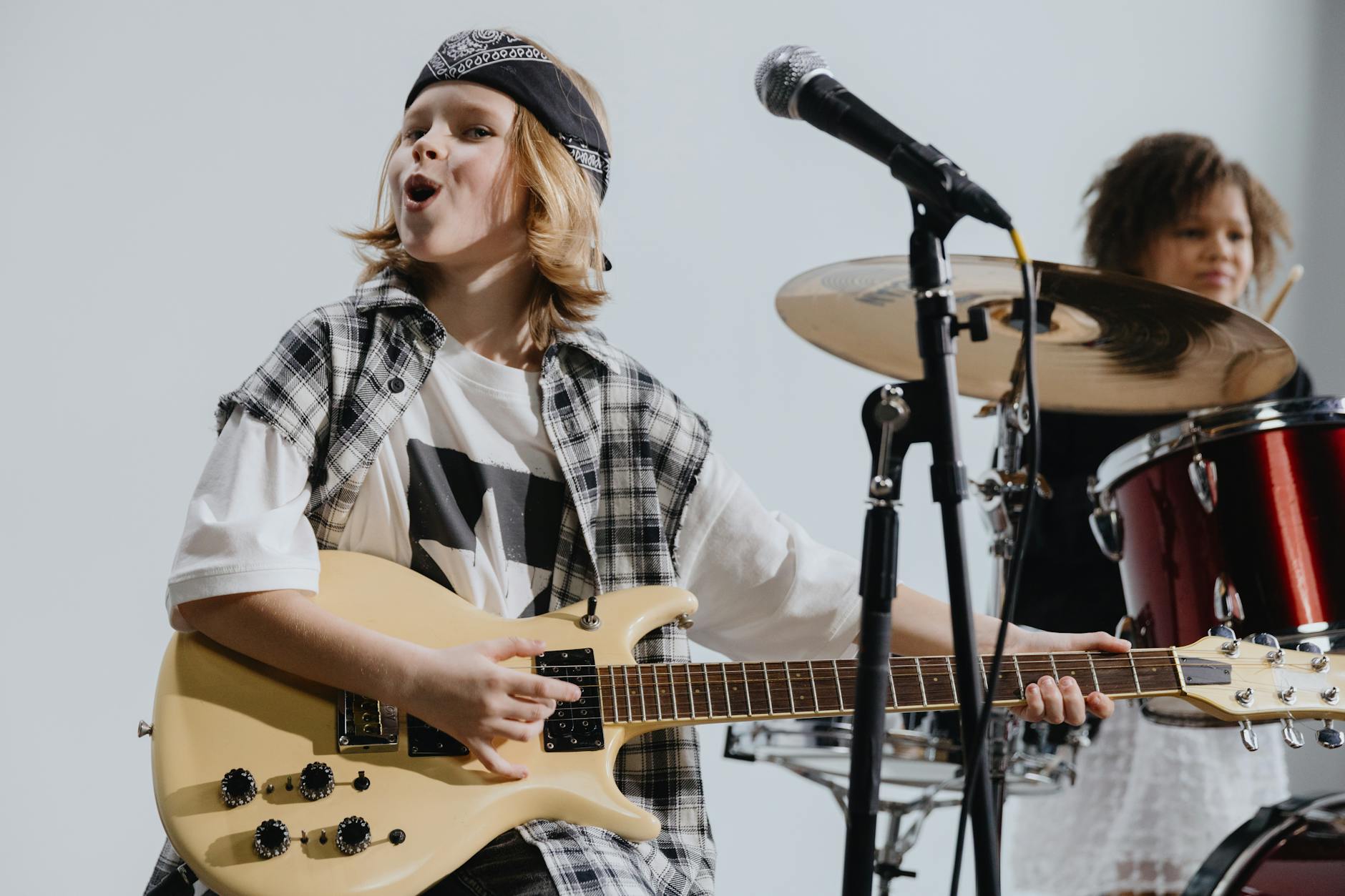 Młodzi muzycy grają na żywo na gitarze i perkusji na scenie
