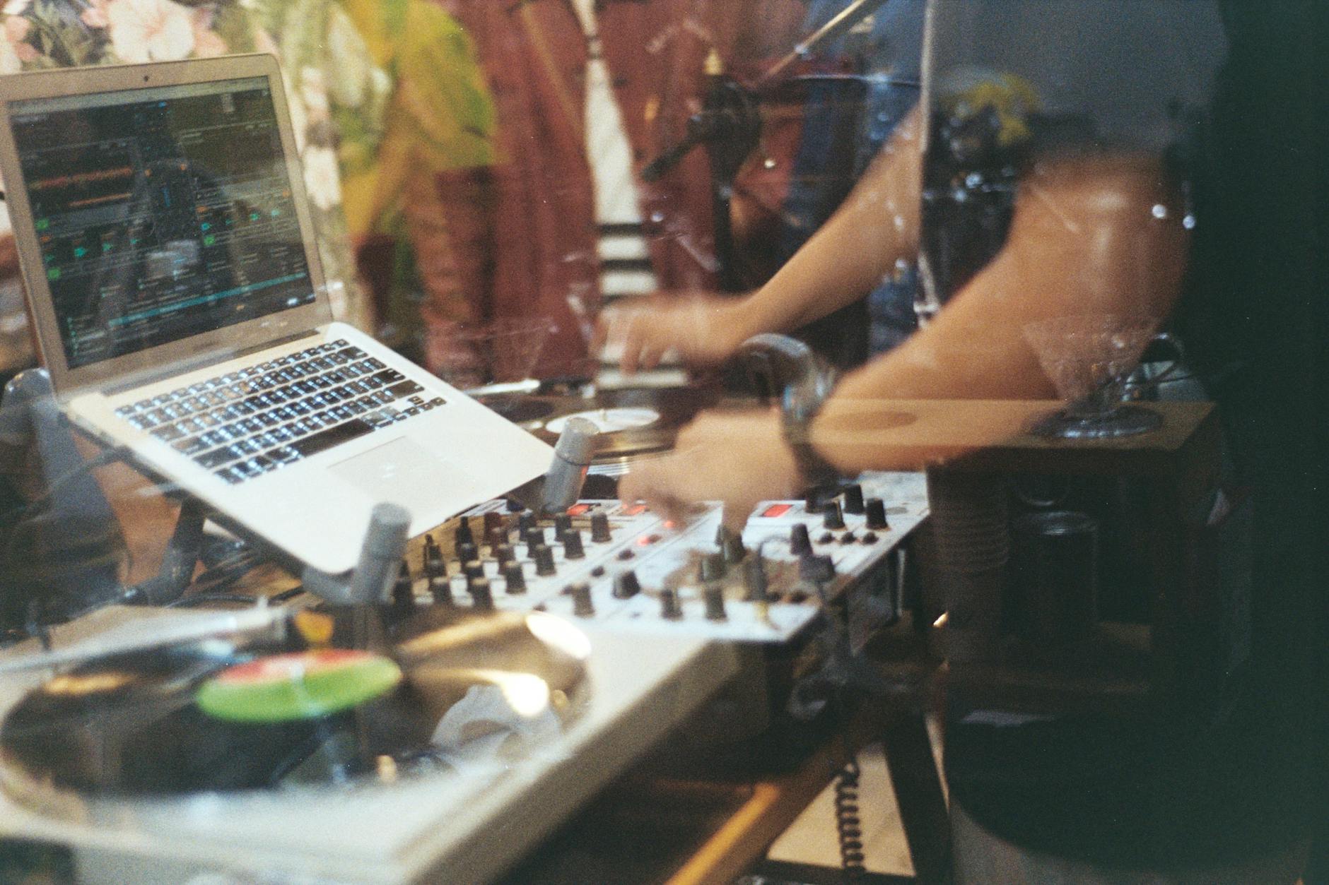 DJ przy konsolecie mikserskiej z winylami i laptopem w studiu