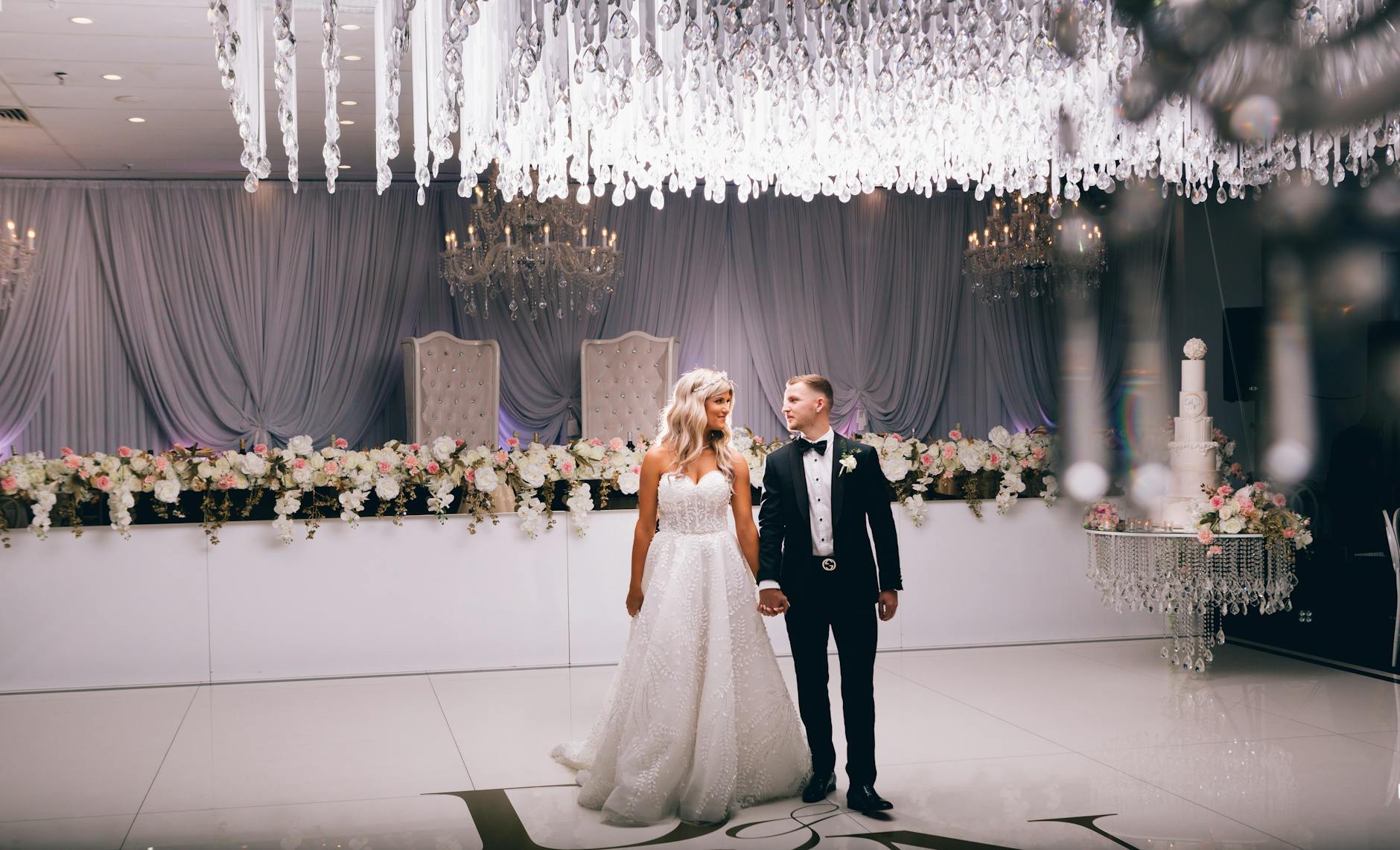 Para młoda na eleganckim przyjęciu weselnym z żyrandolami i kwiatami