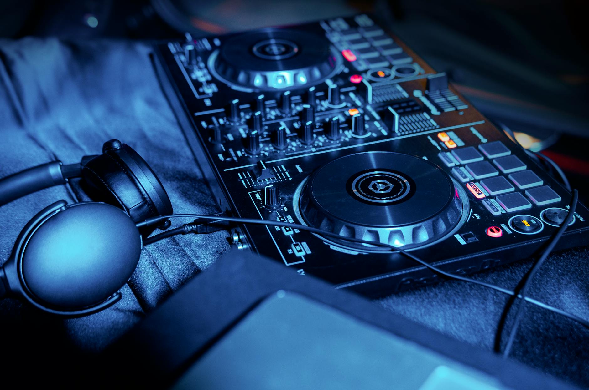 Stół mikserski DJ z słuchawkami w niebieskim świetle na sali weselnej