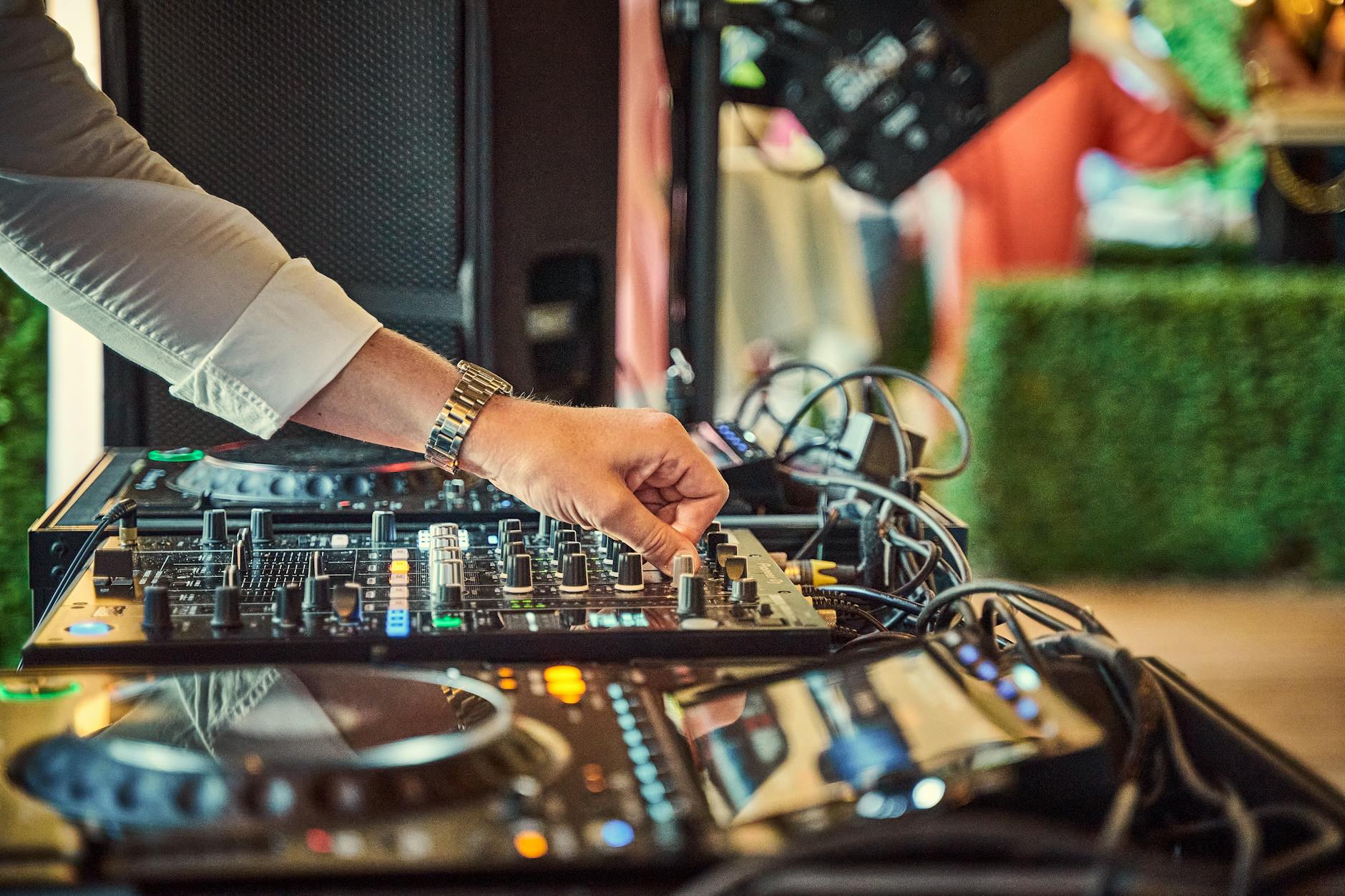DJ reguluje mikser z nowoczesnym nagłośnieniem na weselu na świeżym powietrzu