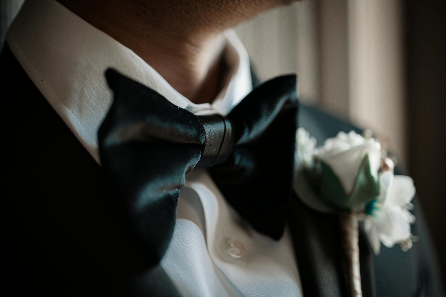 Mucho mężczyzny w smokingu z muszką i butonierką na eleganckim weselu
