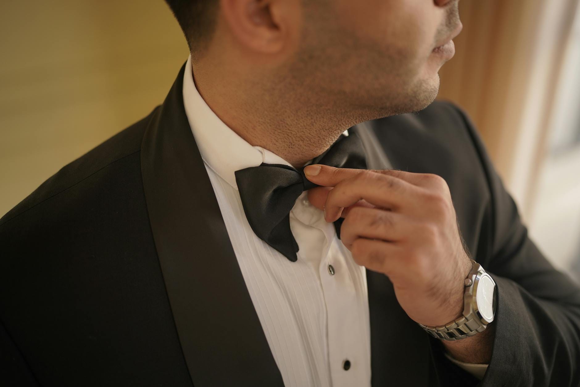 Pan młody poprawia muchę przy klasycznym smokingu black tie