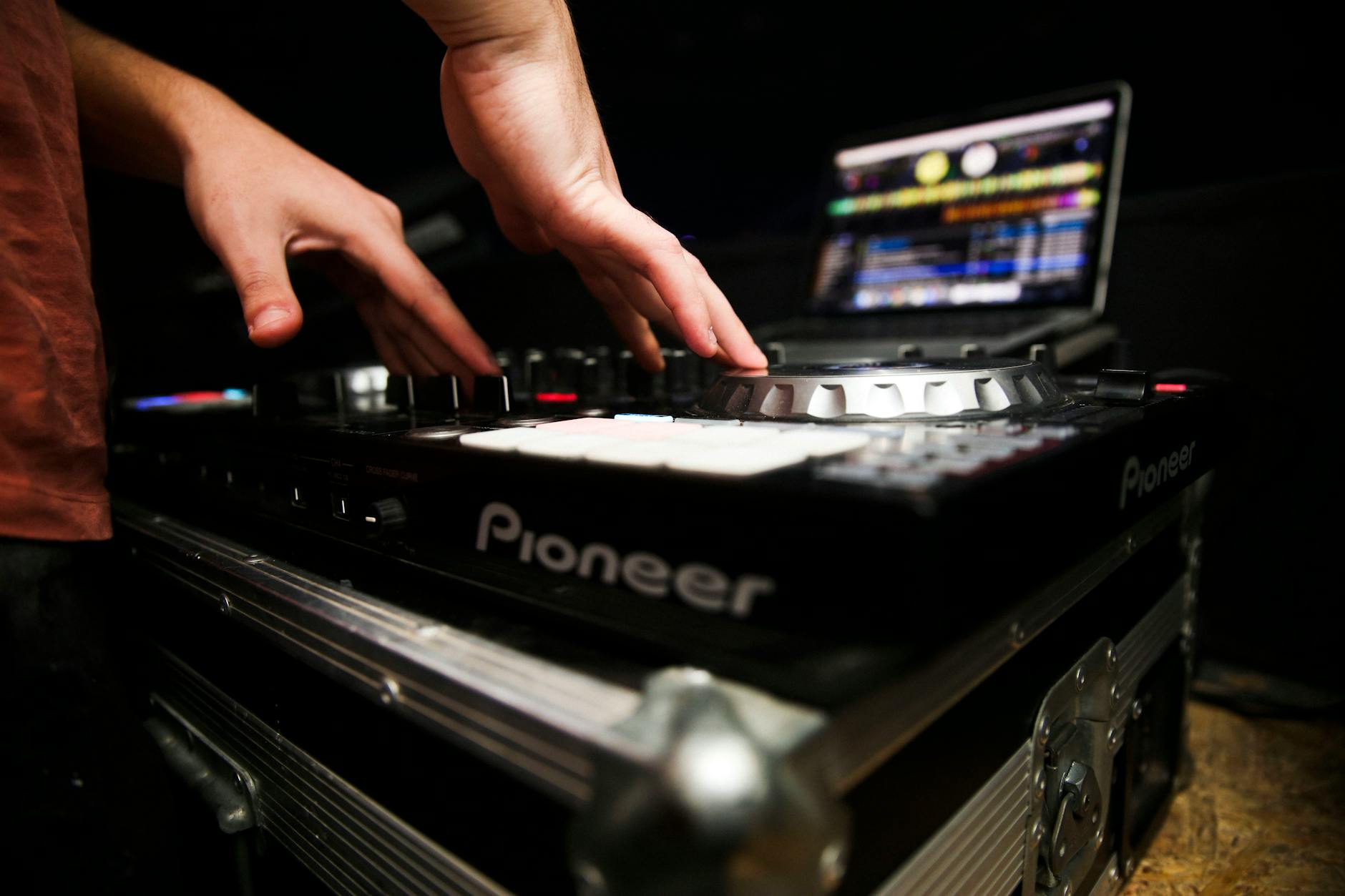 Ręce DJ-a regulujące mikser i kontroler w klubie