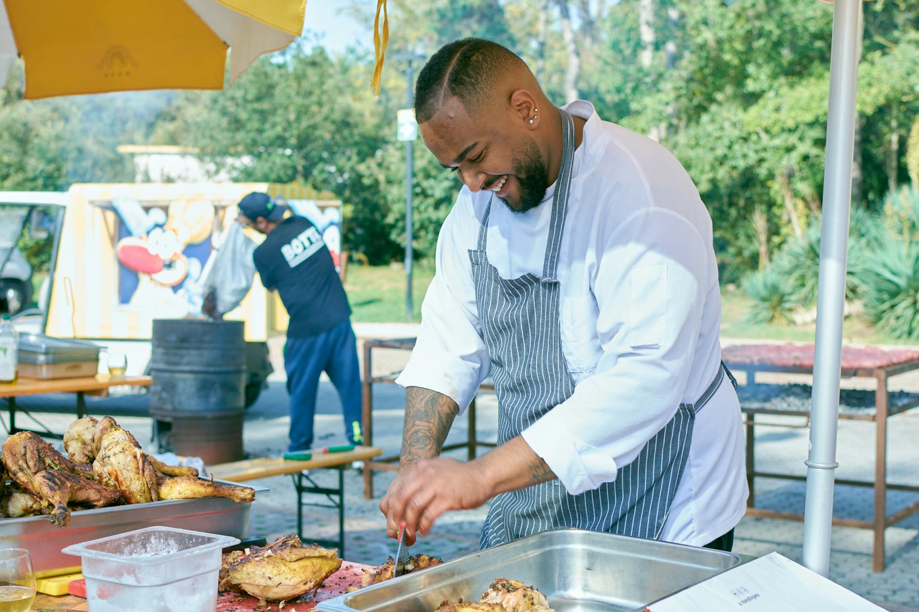 Uśmiechnięty kucharz grilluje kurczaka na plenerowym stoisku gastronomicznym