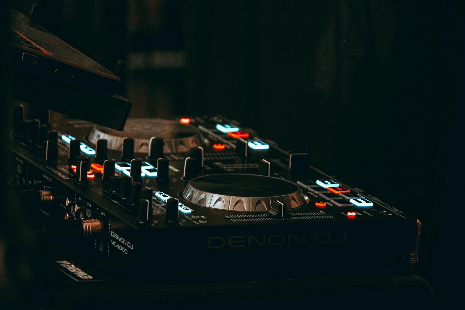 Zbliżenie miksera Denon DJ z podświetlonymi przyciskami i suwakami