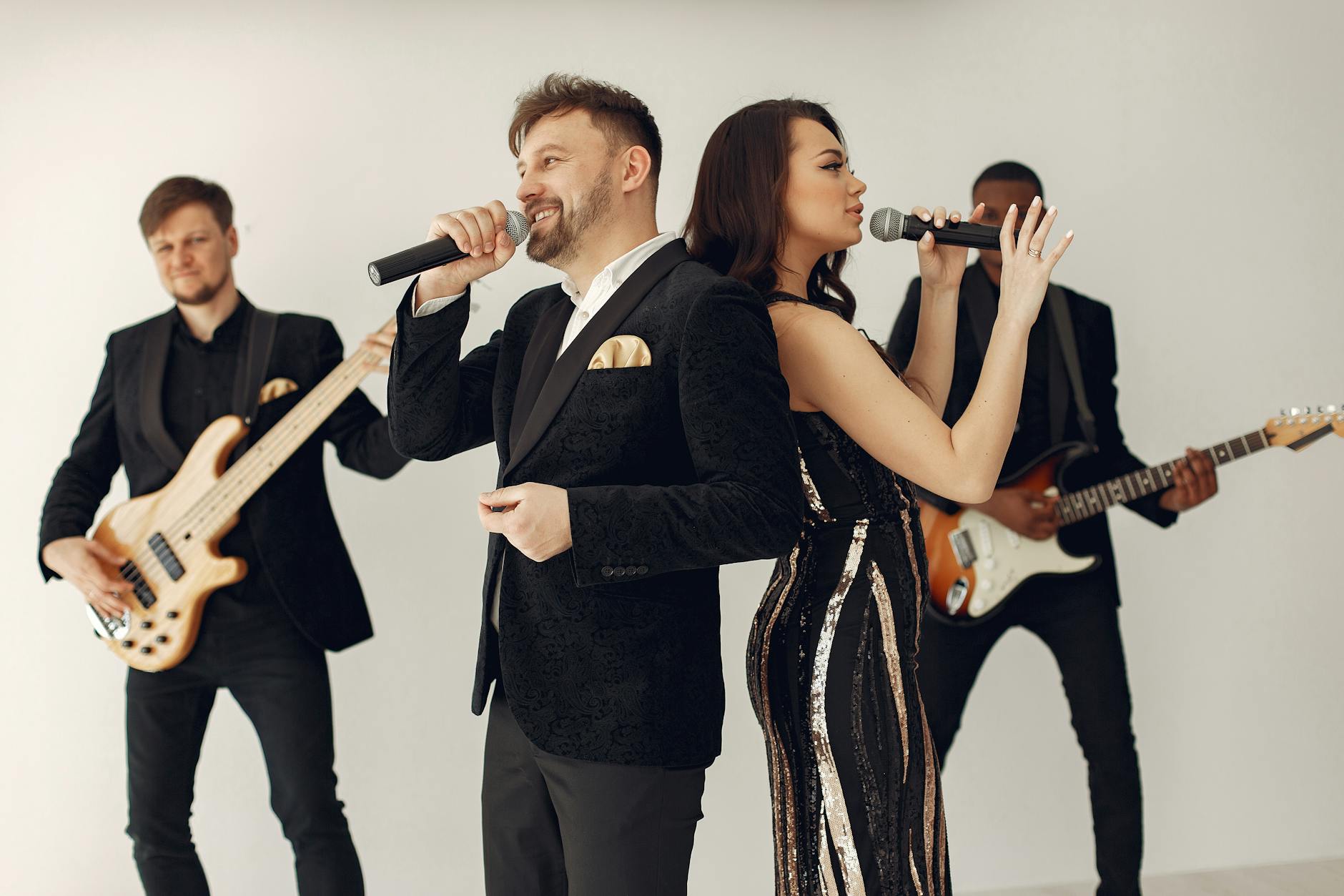 Zespół weselny z wodzirejem śpiewający na oświetlonej scenie