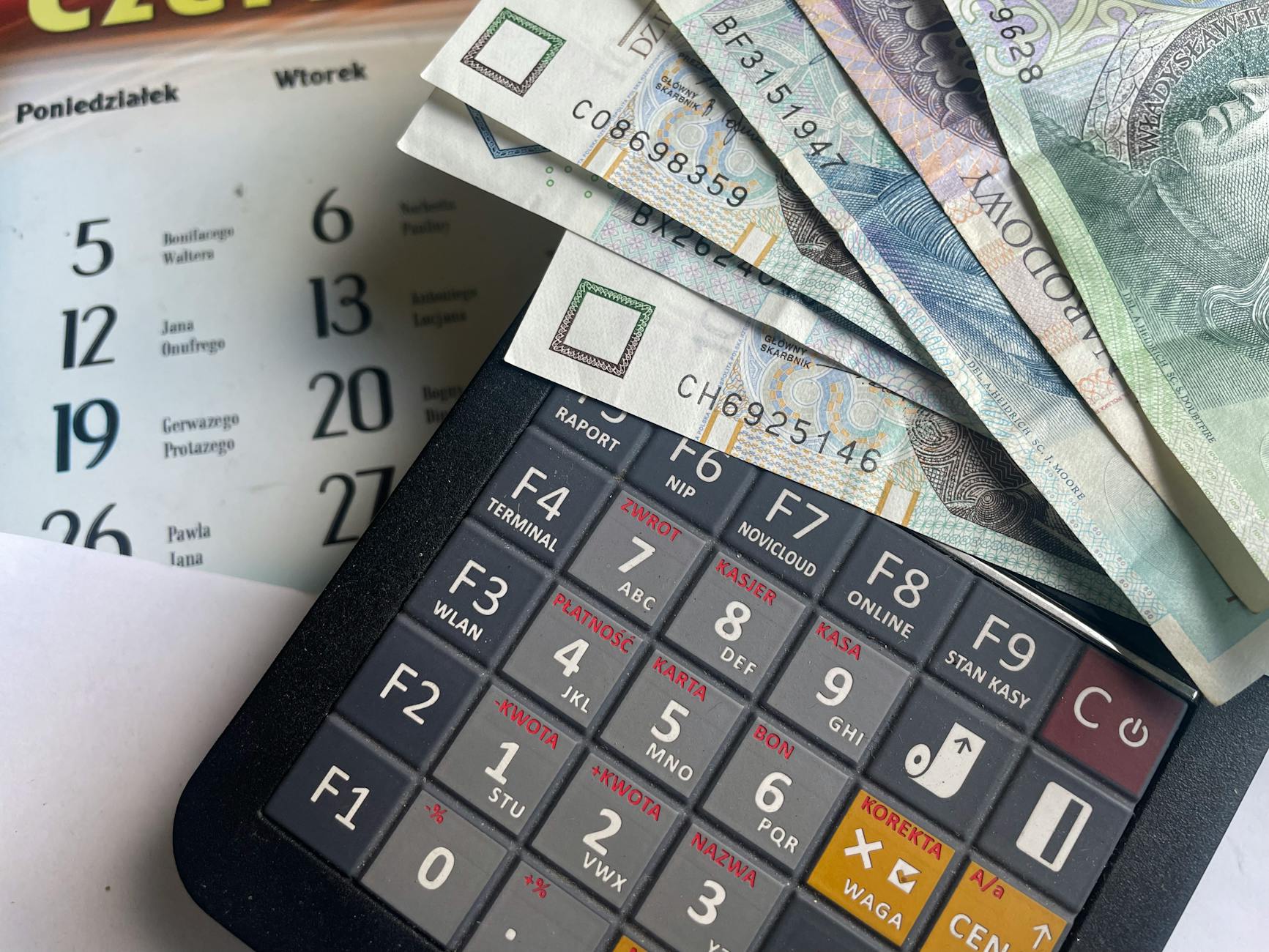 Banknoty złotowe na kalkulatorze z kalendarzem w tle