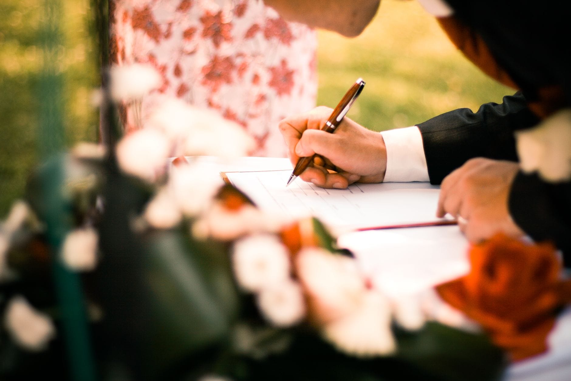 Zbliżenie dłoni podpisujących umowę na ceremonii w plenerze